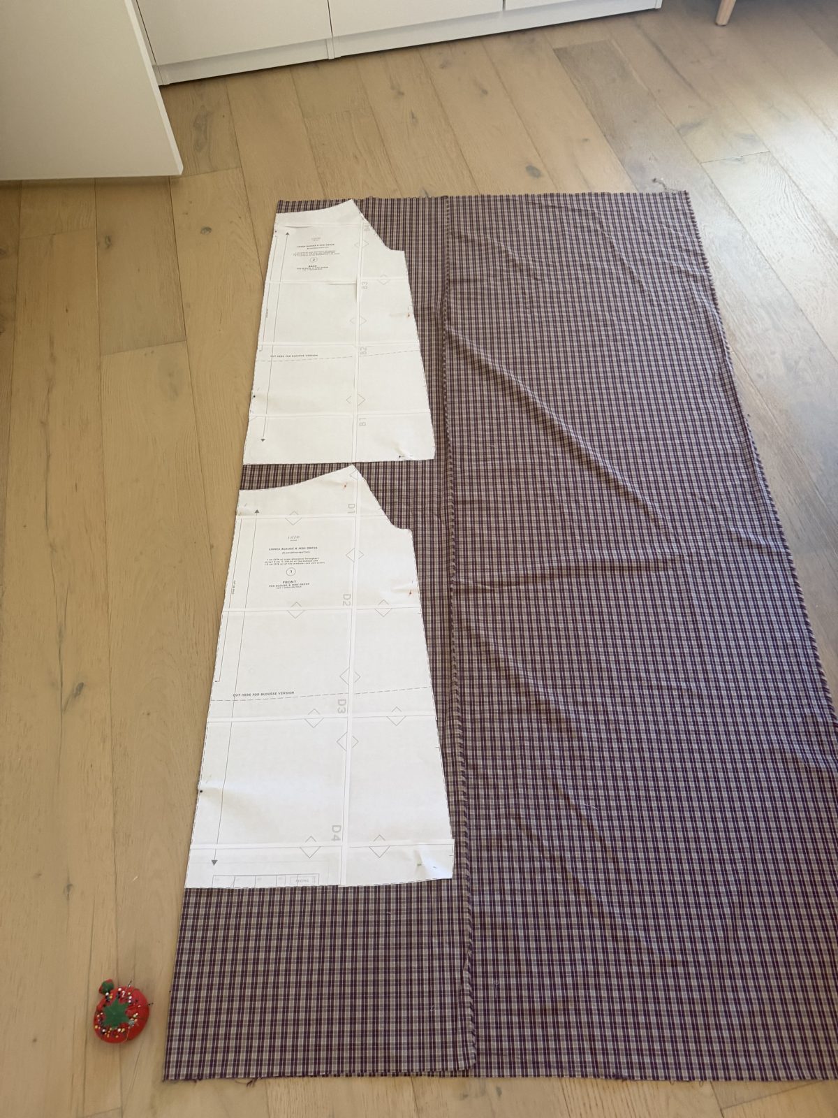 Linnea pattern pieces laid out on the Juice Box 90s Plaid cotton on the floor, ready to cut